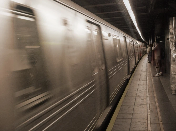 a man standing on a platform next to a subway train