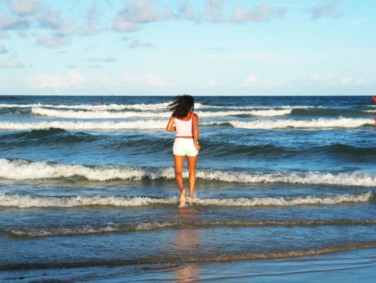 two people walking on the beach as they walk away from the water