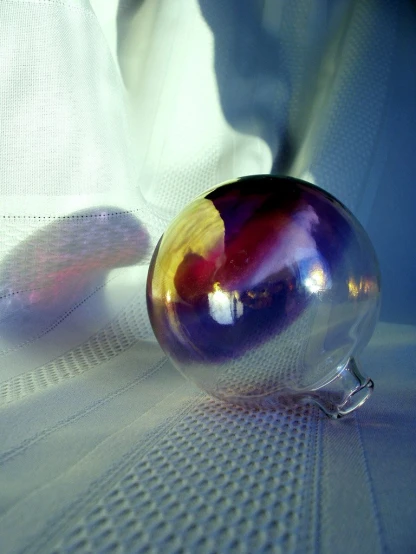 a shiny purple and red object sitting on a cloth