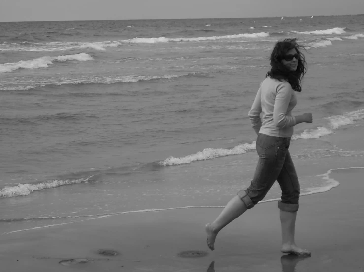 a woman is walking along the beach in her tights