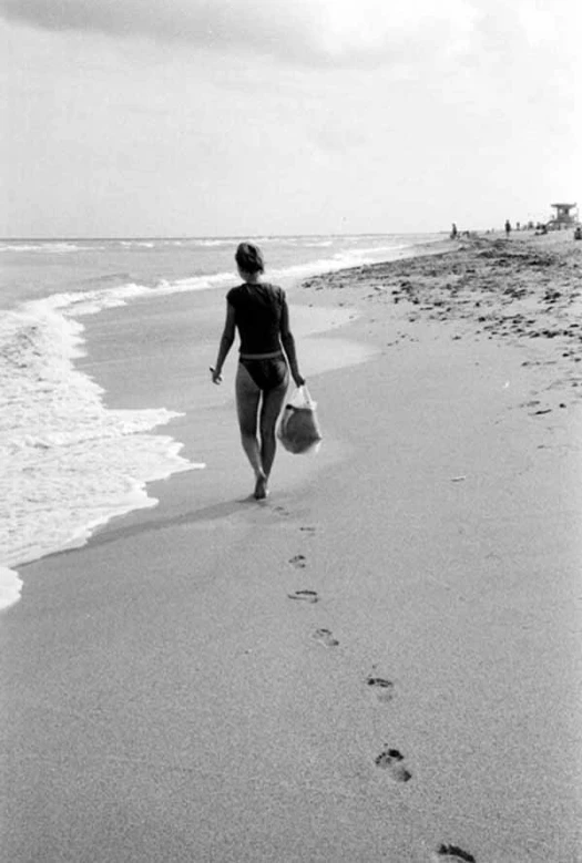 a woman walking on a beach near the water