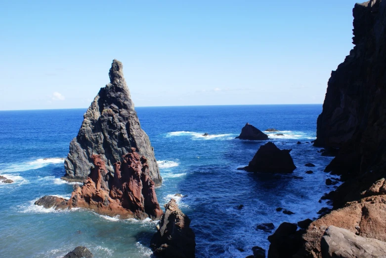 the ocean is clear, blue and there are rocks sticking out of the water