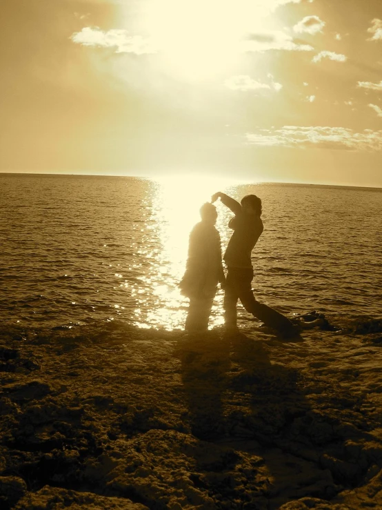 two people in silhouette are standing in the water