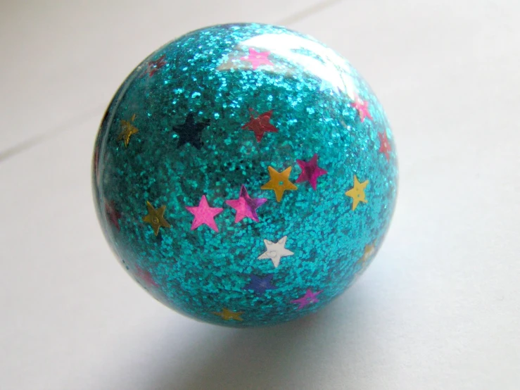 a blue, purple, and pink glittered ball is laying on a table