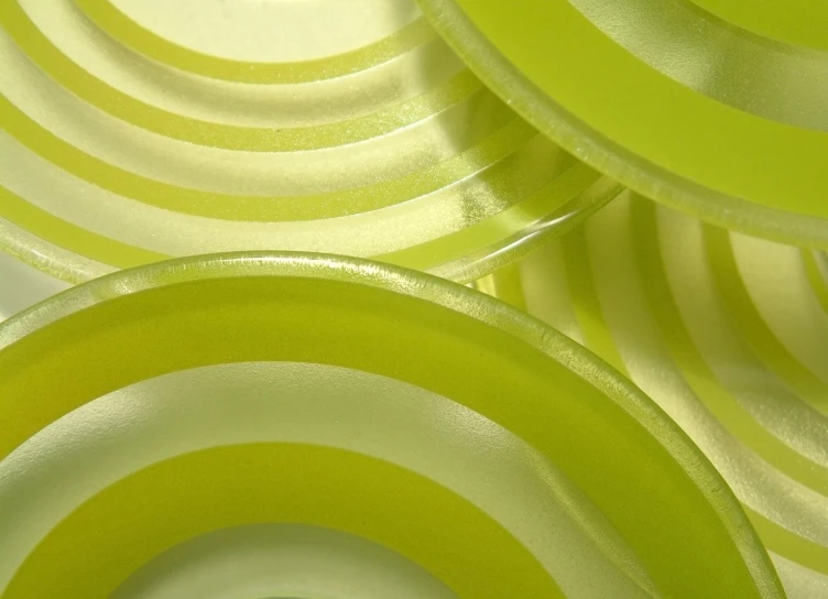 four round yellow and green plates arranged in a pile