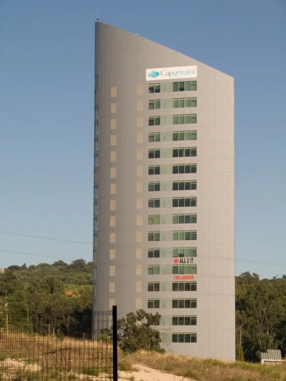 a tall building with a white top sits next to some grass