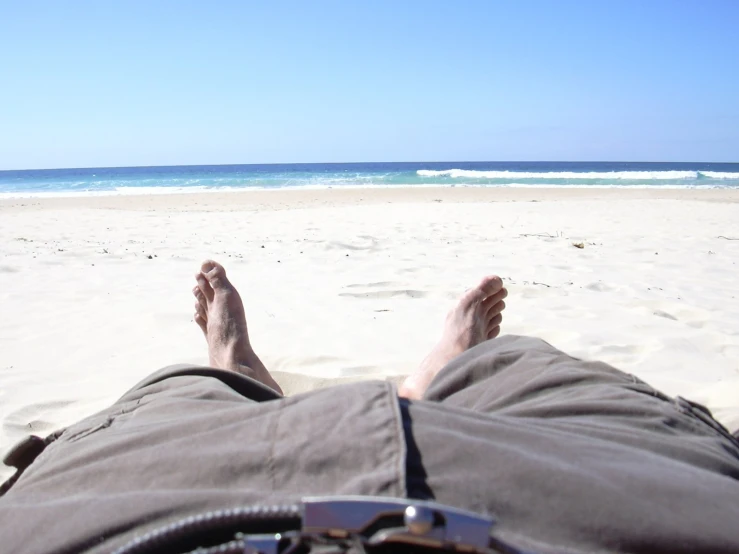 someone has fallen down at the beach and feet are up