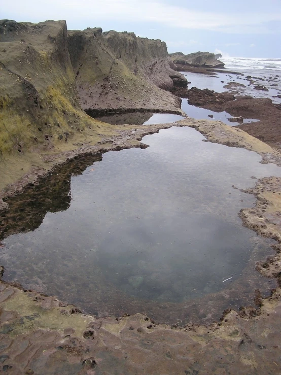 some very dirty water on some rocks by the beach