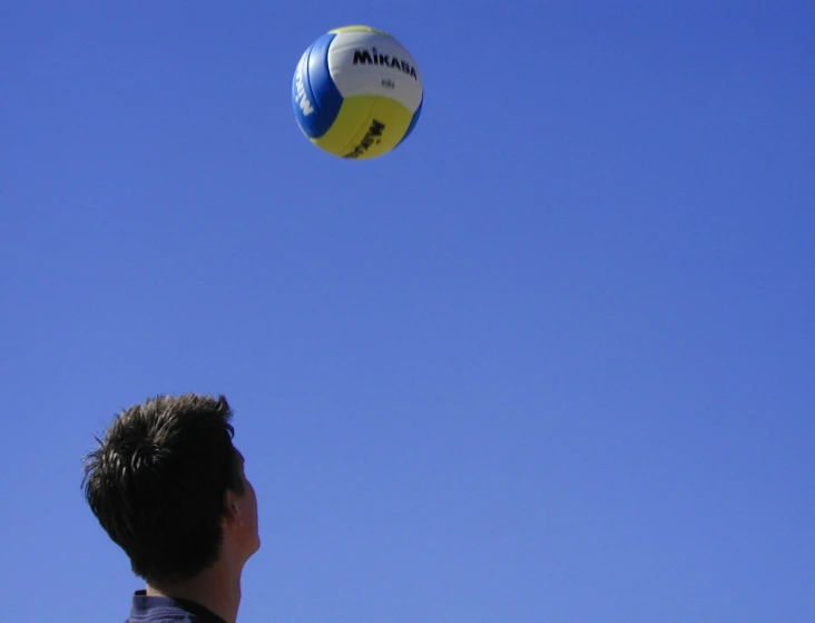 the man is flying a volley ball high in the sky
