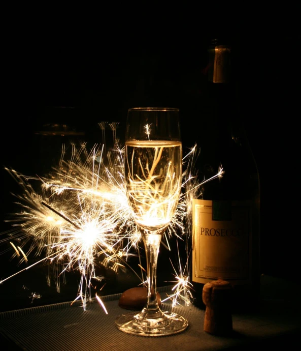 fireworks in wine glass next to bottle of wine