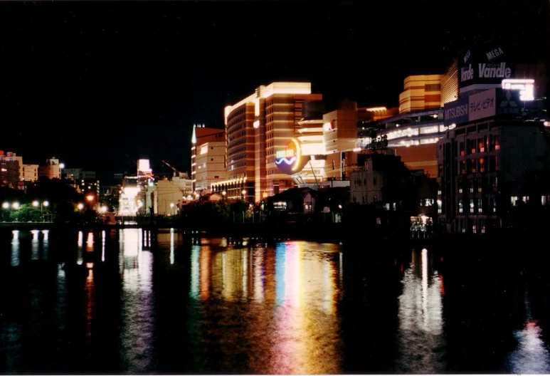 buildings are lit up next to a body of water