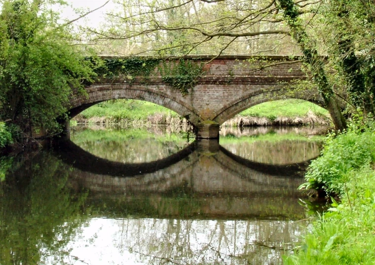 this is an image of the view over the river with a bridge and trees on the bank