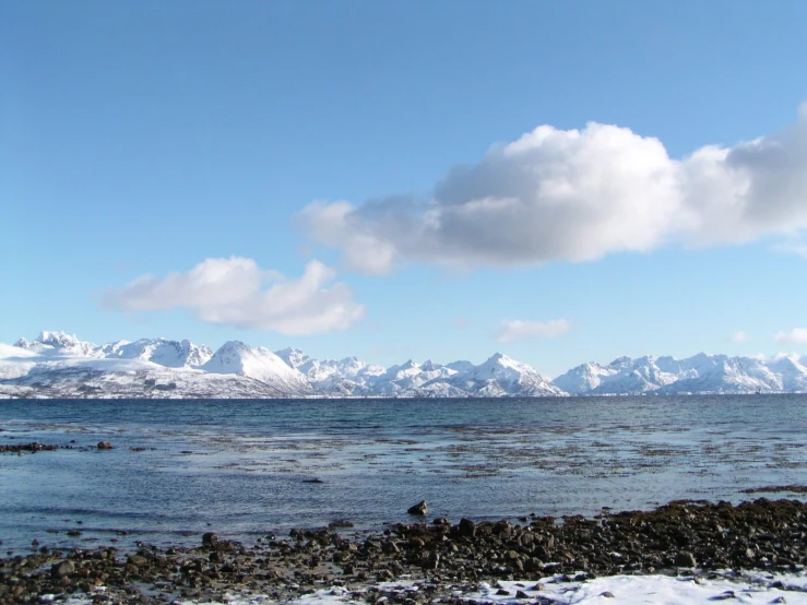 the water in front of snow covered mountains