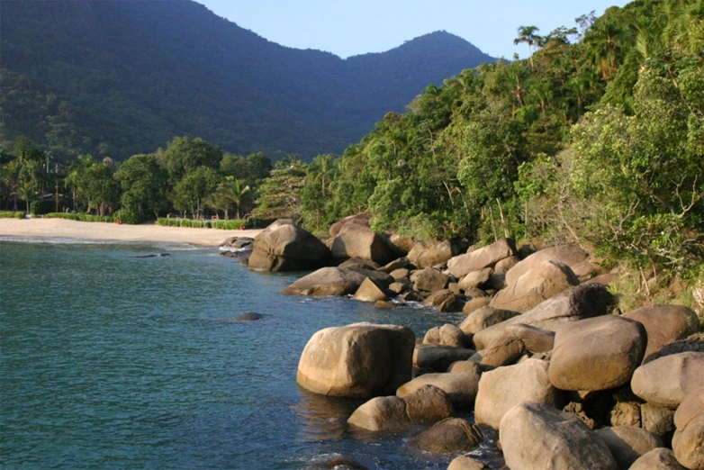 a beach with some large rocks on the shoreline