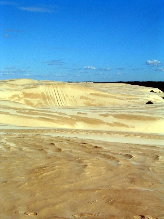 sand dunes under a partly cloudy blue sky