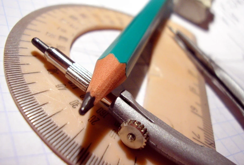 a pencil sitting on a ruler with an orange piece of wax paper