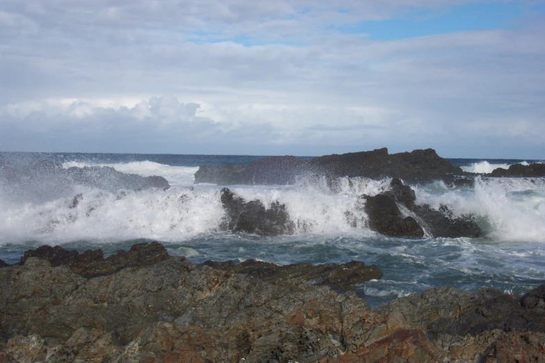 ocean waves crashing into the rocks along the shore