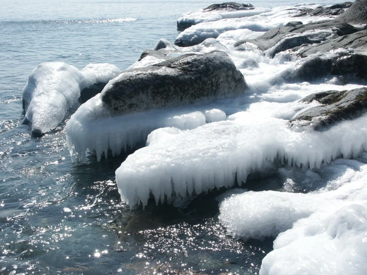 some rocks are melting in the water by a shore