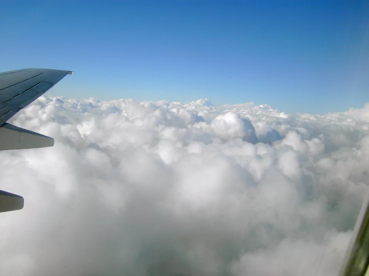 airplane wing flying above a layer of clouds