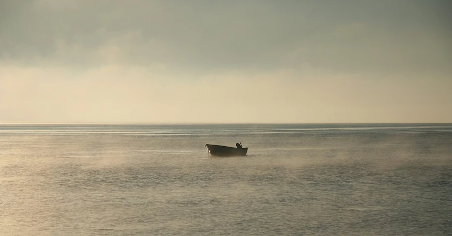 boat traveling across water and with fog on the horizon