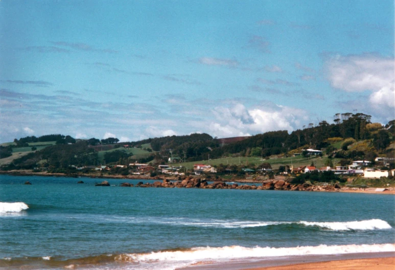 the shore of a beach with houses and boats in the water