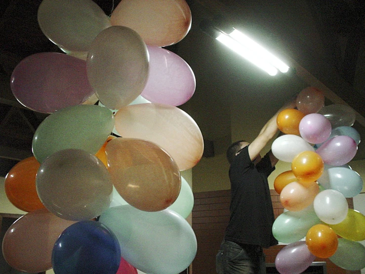 a young man standing next to a wall holding balloons