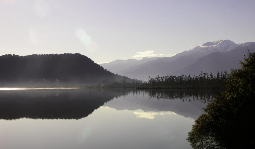 the reflection of trees in water near mountain