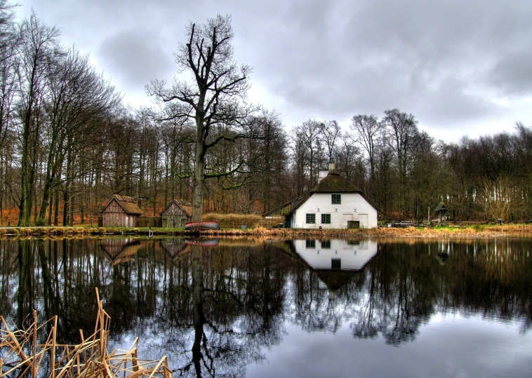 a white house is next to trees and water