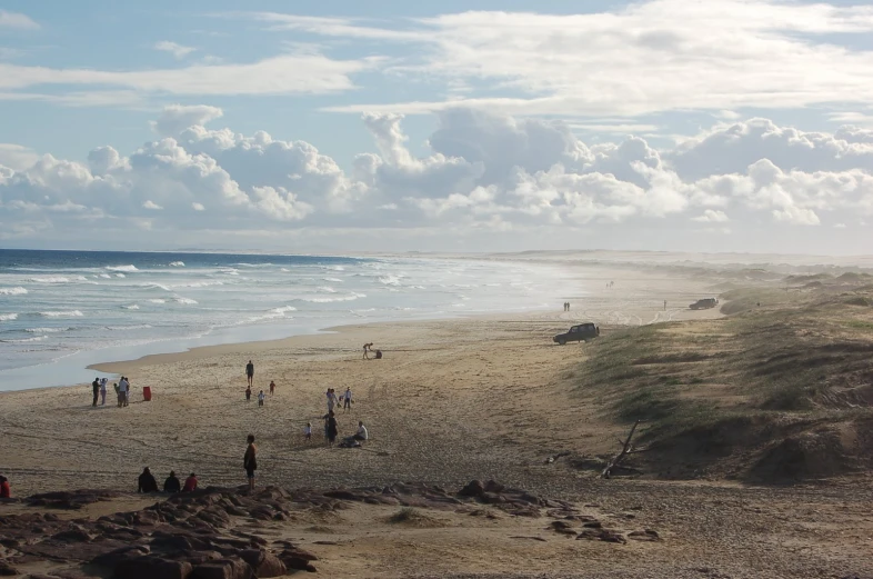 a group of people walk along the beach on a sunny day