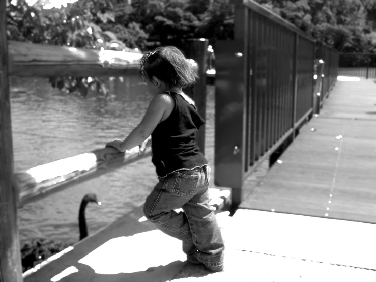 a black and white image of a toddler walking on the dock