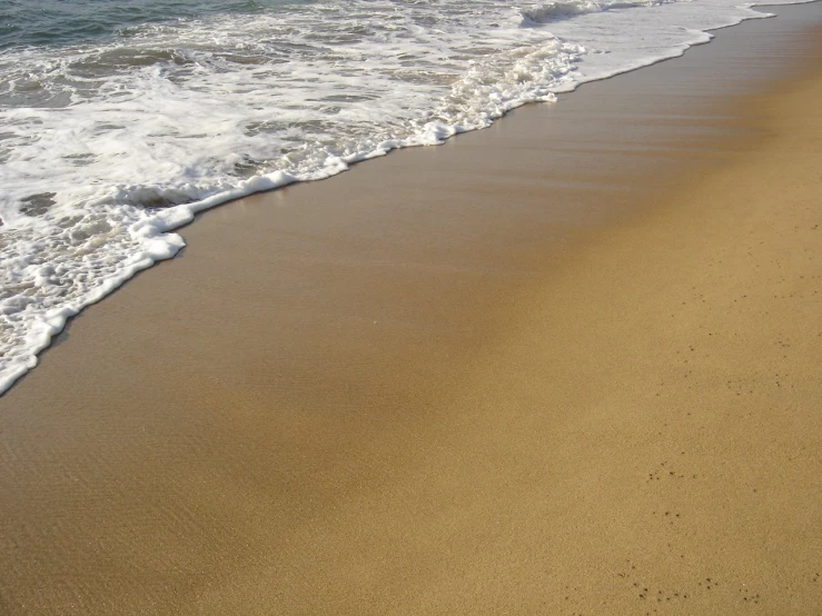 the beach has white capped waves coming in from the water