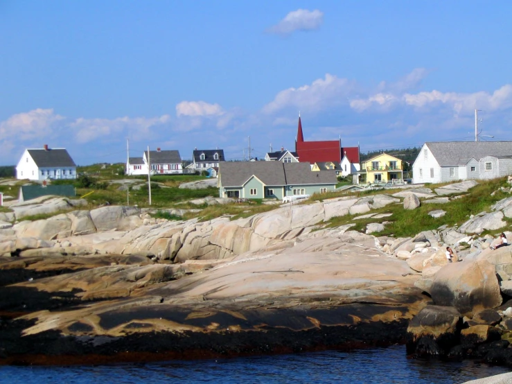 houses sitting on the side of a rocky hill with water below them