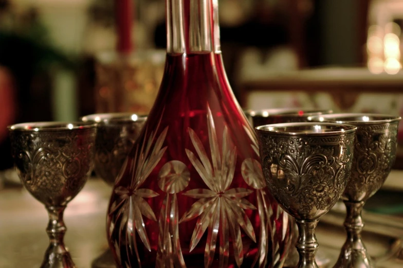 a red vase with silver glasses on top