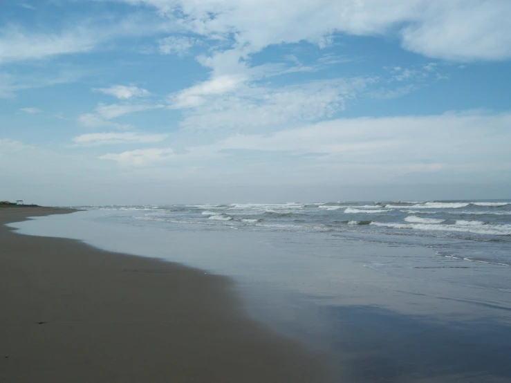 a beach has white sand, water and some waves