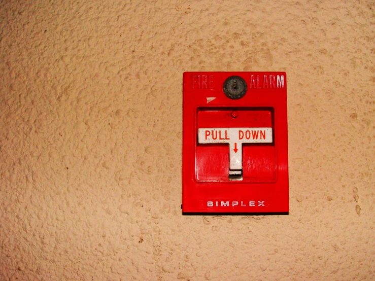 a red light switch sitting on top of a sandy wall