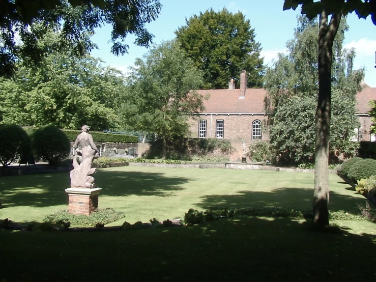 a yard with trees, bushes and an old building