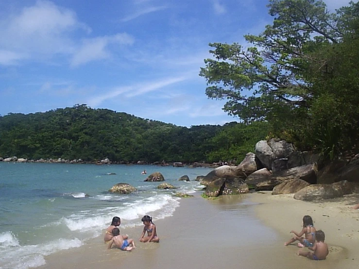 a group of people standing in the surf at the beach