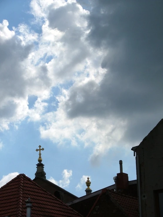 a bird flying in the cloudy sky over some roof tops