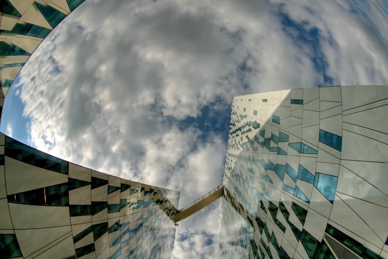 a picture looking up into the sky with a reflection of a building and clouds