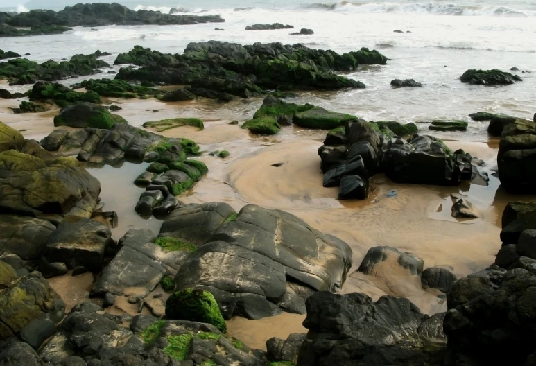 rocks near water on the shore line in front of a body of water