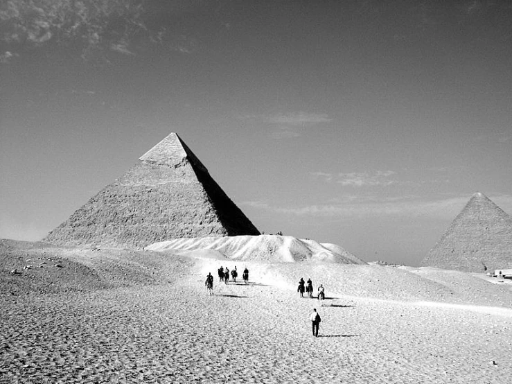 group of people walking up a hill to the pyramids