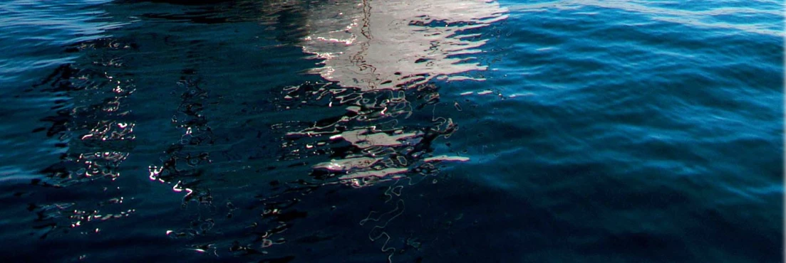 boat in the middle of a blue ocean with a bright reflection