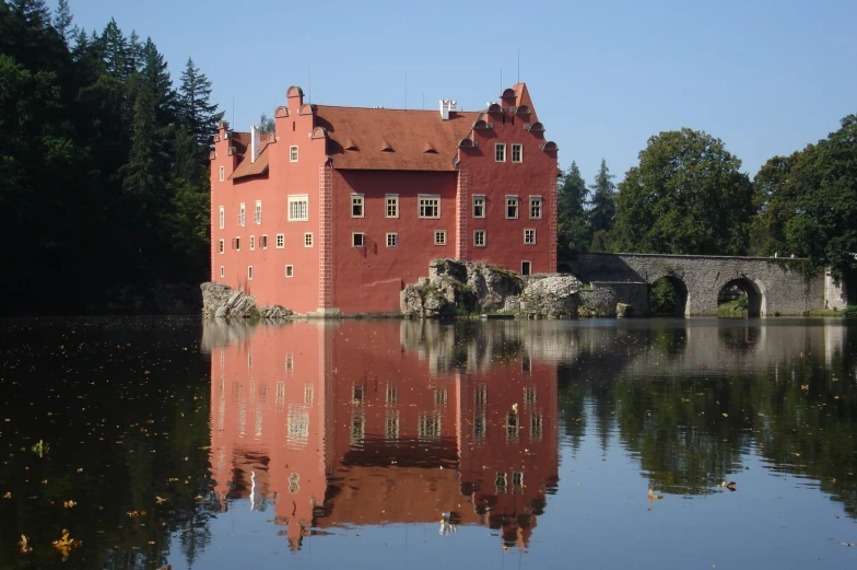 a very red castle house sitting over the water
