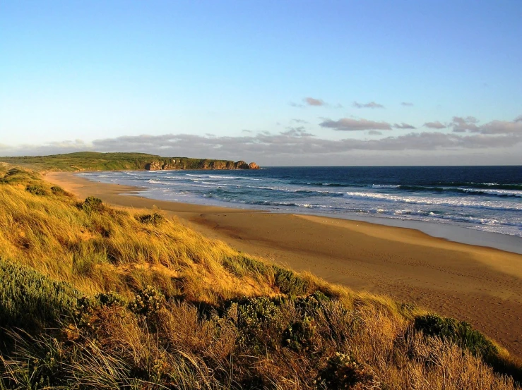 the view from the hill at the beach looking down on the water and land