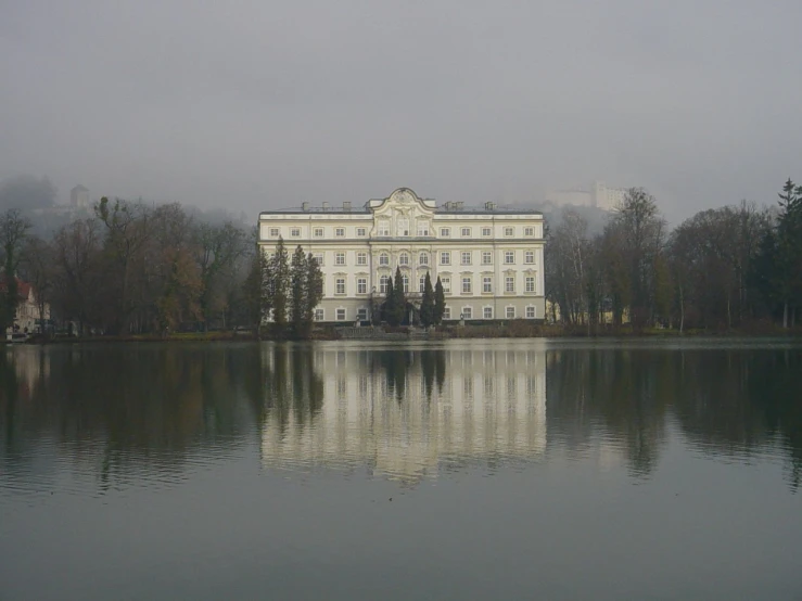 a large, white house on the shore of a lake