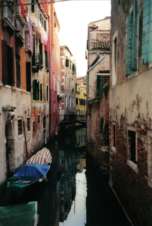 two boats docked in the canal between brick buildings