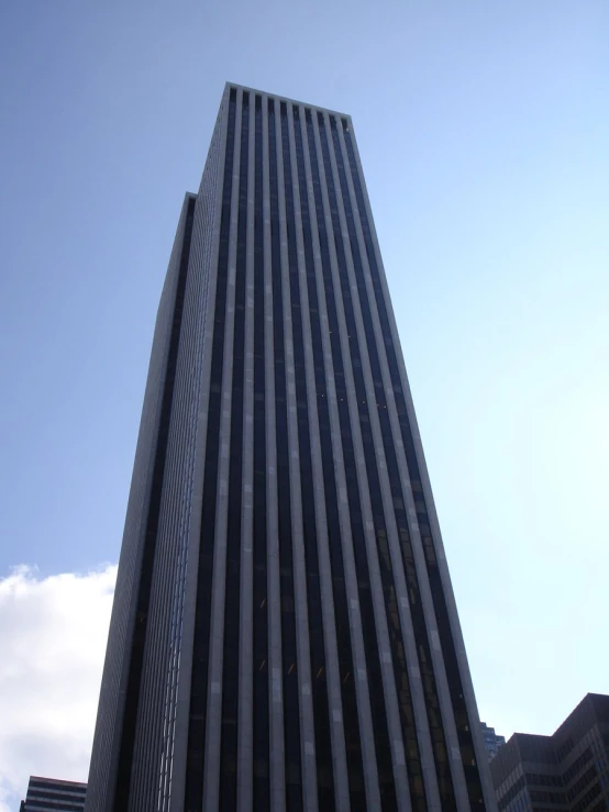 a very tall building near some buildings under a bright blue sky