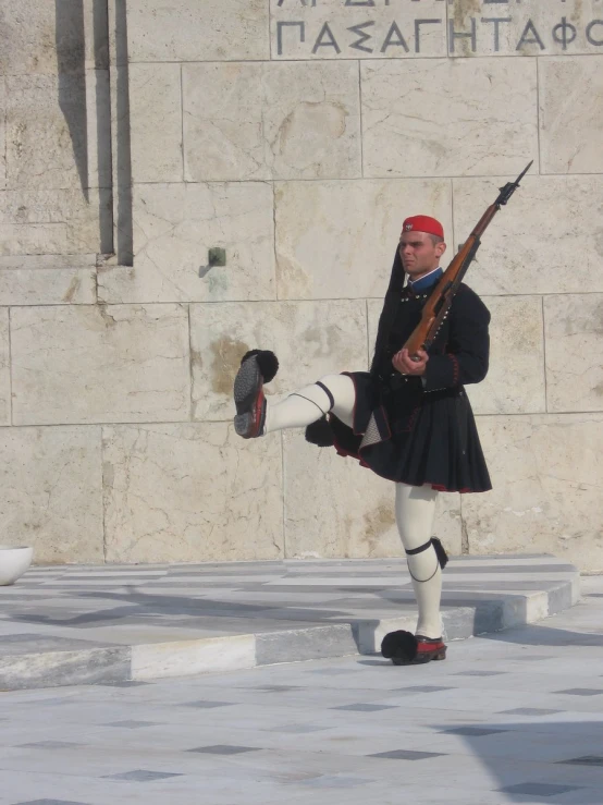 a man in a kilt is holding his rifle and kicking it