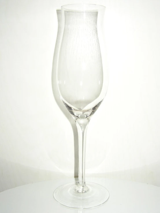 a wine glass on the table with white wall in background