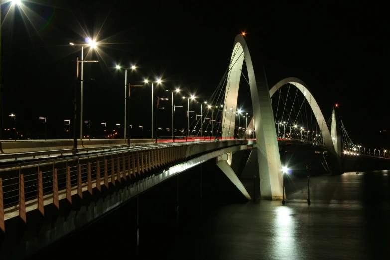 the bridge over the water is lit up at night